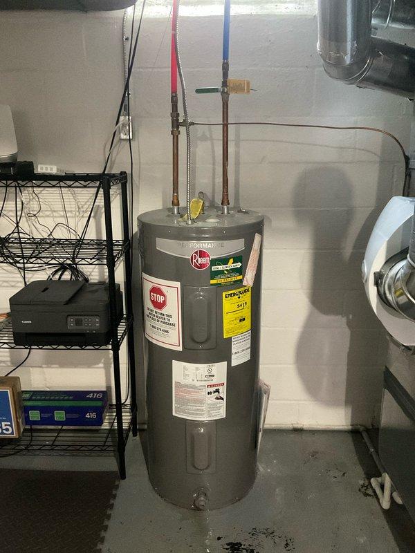 Responded to service call for hot water leaking from bottom of tanked water heater. Upon arrival, inspected Rheem brand water heater unit located in basement utility room. Observed visible water staining and discoloration on concrete floor surrounding base of tank, confirming active leak from lower section of vessel. Determined tank integrity had been compromised, likely due to internal corrosion and sediment buildup consistent with age of home and equipment. Documented condition of unit with photographs showing manufacturer labels, plumbing connections, and evidence of water damage at floor level. Advised that bottom tank leaks indicate failure of steel liner and are not repairable, requiring full water heater replacement to resolve issue and restore hot water service.