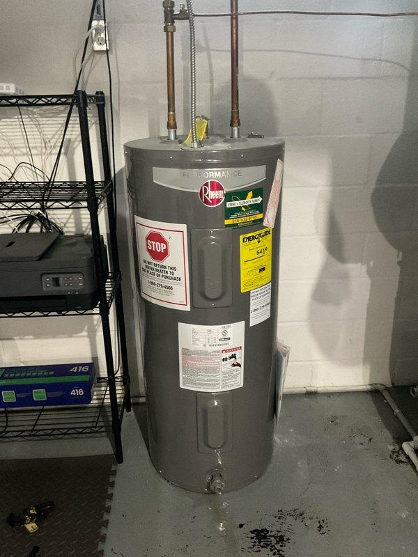 Responded to service call for hot water leaking from bottom of tanked water heater. Upon arrival, inspected Rheem brand water heater unit located in basement utility room. Observed visible water staining and discoloration on concrete floor surrounding base of tank, confirming active leak from lower section of vessel. Determined tank integrity had been compromised, likely due to internal corrosion and sediment buildup consistent with age of home and equipment. Documented condition of unit with photographs showing manufacturer labels, plumbing connections, and evidence of water damage at floor level. Advised that bottom tank leaks indicate failure of steel liner and are not repairable, requiring full water heater replacement to resolve issue and restore hot water service.
