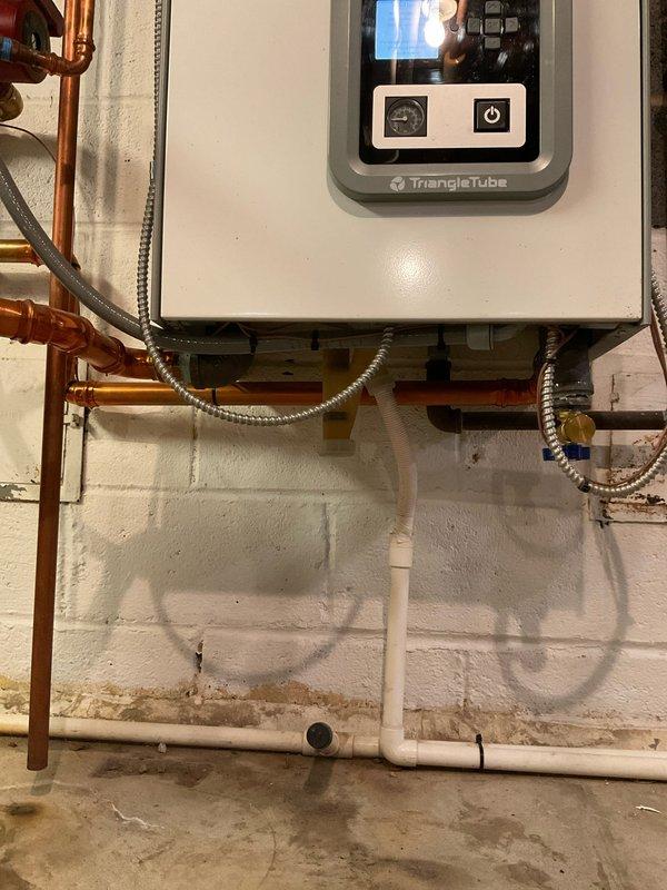 Responded to service call for water heater repair at residential property with 2-year-old Triangle Tube system. Upon inspection, verified proper operation of hydronic heating unit and associated components including expansion tank, copper supply lines, pressure relief valves, and zone control valves. System showed normal operating parameters with expansion tank maintaining appropriate pressure and all shut-off valves functioning correctly. Documented existing installation configuration including PVC condensate drainage, flexible metallic conduit connections, and brass valve assemblies with red handles for system isolation and maintenance access.