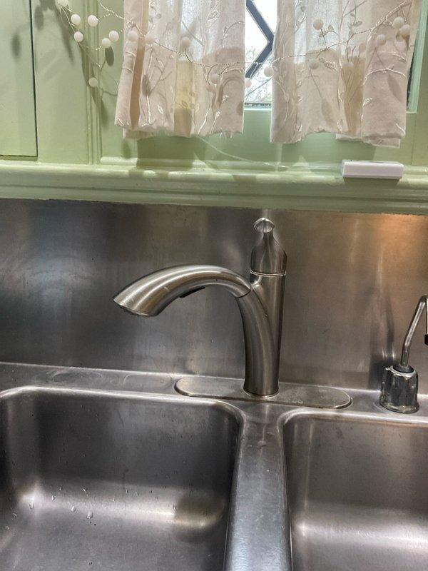 Responded to service call for slow drainage issues affecting kitchen faucet, bathroom sink, and tub drain in a 1930s-era home. Assessed existing plumbing system and identified drainage concerns related to aging infrastructure. Removed old kitchen faucet and installed customer-provided replacement unit, ensuring proper mounting and connection to existing supply lines. Addressed slow drainage problems in multiple fixtures by clearing obstructions and evaluating the condition of vintage drain assemblies and P-trap configurations. Inspected under-sink plumbing, noting deteriorated components and aging PVC trap assembly with visible wear. Restored proper water flow and drainage function to all affected fixtures. Tested new faucet installation for leaks and verified adequate water pressure and drainage performance throughout the system.
