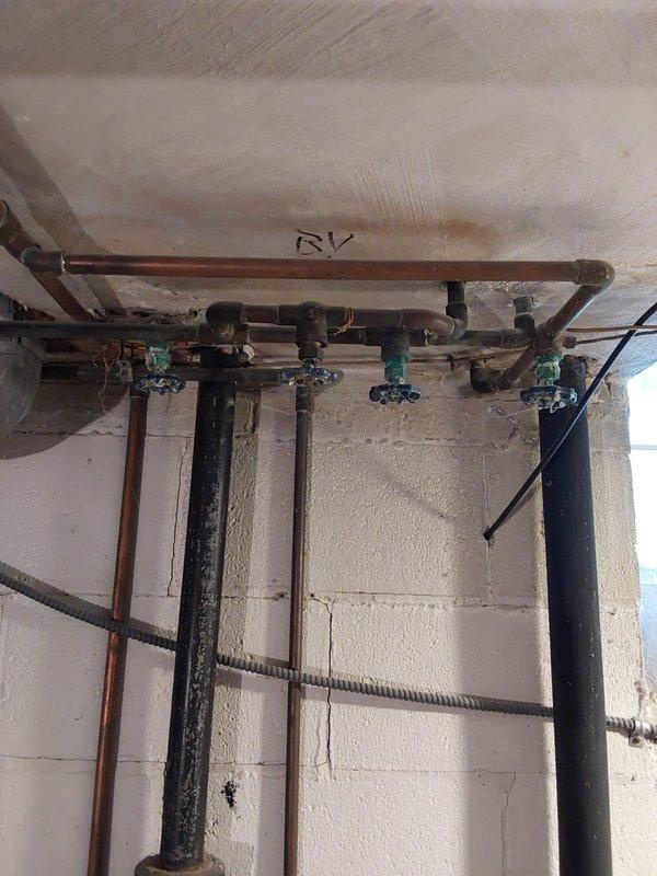 Completed comprehensive plumbing assessment for tankless water heater conversion feasibility in residential utility space. Evaluated existing plumbing infrastructure including copper manifold system with multiple branch lines, shut-off valves, and distribution piping, as well as current water heater connections featuring aged gate valves and flexible supply lines. Documented electrical panel capacity concerns and provided recommendations for panel upgrade options if required to support tankless unit installation.