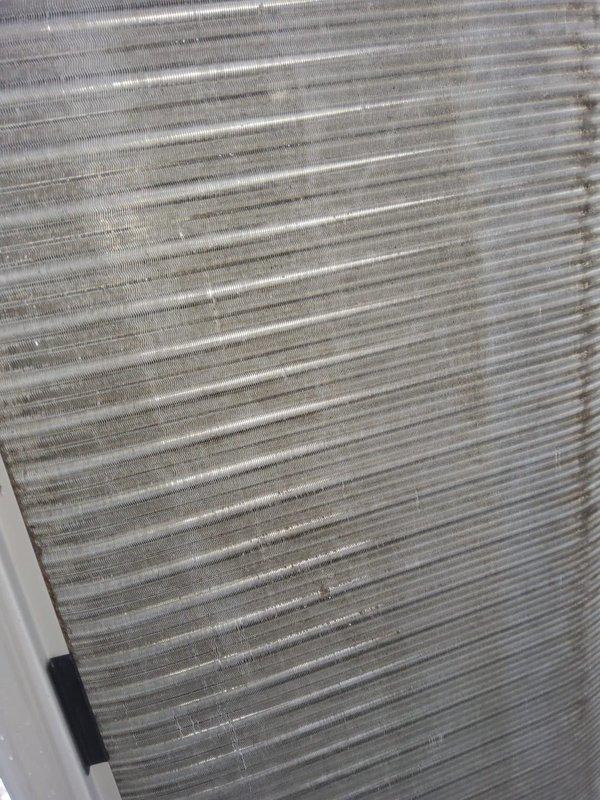 Completed scheduled cooling system tune-up and preventive maintenance inspection. Examined outdoor condenser unit coil assembly, noting moderate dust and debris accumulation on aluminum heat exchanger fins affecting airflow efficiency. Documented current condition of finned coil surfaces showing typical operational wear and environmental exposure consistent with regular system use.