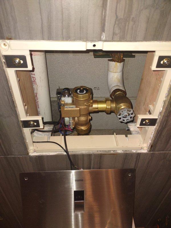 Completed toilet repair service requiring two technicians over a six-hour period in a commercial bathroom facility. Accessed and serviced wall-mounted TOTO toilet system through existing access panel, addressing plumbing valve assembly and associated electrical connections. All fixtures restored to proper working order, access panel secured, and area left clean and operational.