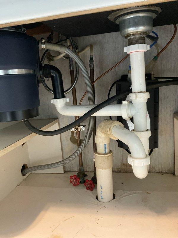 Completed professional installation of customer-supplied kitchen sink in granite countertop over a two-day service period. Installation included mounting stainless steel double-basin sink, installing modern single-handle pull-down faucet with brushed metal finish, and configuring complete under-sink plumbing assembly with garbage disposal unit, PVC P-trap drainage system, copper water supply lines, and shut-off valves. All components tested and verified operational upon completion.