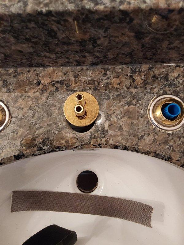 Completed installation of brass wall-mounted faucet valves and fixtures on bathroom vanity with granite countertop. Installed escutcheon plates, valve stems, and connected chrome supply lines to ensure proper water flow to sink basin. All fixtures secured and tested for functionality.