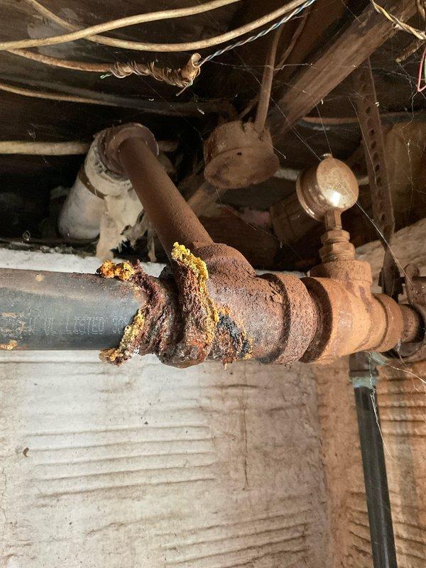 Responded to water leak in basement of 106-year-old residential property. Upon arrival, located source of leak in crawl space beneath main floor. Inspection revealed severely corroded galvanized steel supply piping with extensive rust deterioration at multiple joints and valve connections. Primary leak originated from compromised vertical pipe section where corrosion had penetrated through pipe wall at coupling assembly.

Shut off main water supply to prevent further water damage. Removed failed corroded pipe section and associated fittings exhibiting structural compromise from rust buildup and mineral deposits. Cut out approximately four feet of deteriorated galvanized piping. Installed new copper pipe section with compression fittings and brass shutoff valve to replace corroded assembly. Secured new piping to floor joists with appropriate hangers and supports.

Tested system for leaks by restoring water pressure and monitoring all connections for twenty minutes. Verified no active le