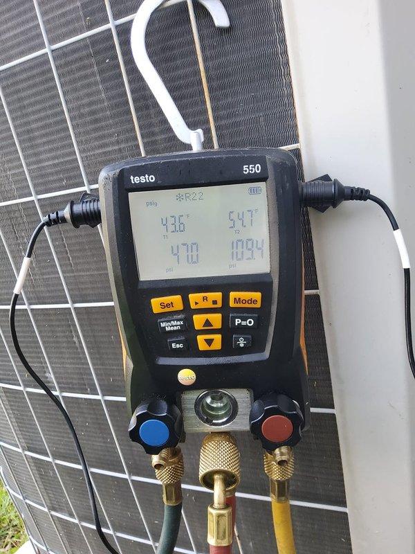# HVAC Maintenance - Cooling System Service

Performed comprehensive preventive maintenance on a 15+ year old heat pump/air conditioning system utilizing R-22 refrigerant. This was the first service call for this MVP customer, conducted during the morning service window.

## Work Performed

Conducted complete system diagnostics using calibrated Testo 550 digital manifold gauge set to evaluate system performance and refrigerant charge. Connected gauges to service ports and recorded operating pressures and temperatures across the system. High-side pressure reading of 470 psig and low-side pressure of 109.4 psig were documented during operation. Temperature measurements showed 43°F on the suction line and 54°F at the liquid line, with ambient conditions at 28.1°F indicated on the instrument display.

Performed visual inspection of outdoor condenser unit, examining coil condition, electrical connections, and overall system integrity. Assessed the heat exchanger fins and condenser coil for 
