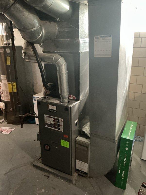 Conducted estimate for potential AC replacement in residential property with existing furnace and water heater system located in basement mechanical room. Evaluated current HVAC system capacity and determined unit may be undersized for the home's cooling requirements, including converted attic office space with multiple electronic devices generating additional heat load. Documented existing equipment configuration and ductwork layout with photographs for replacement proposal preparation.