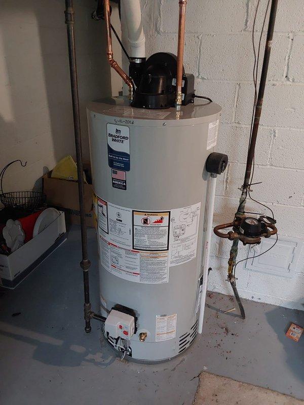 Responded to service call for leaking water heater at 60-year-old single-family residence. Upon inspection, diagnosed failed tank requiring complete replacement due to active leak. Removed existing deteriorated water heater and installed new Bradford White tanked unit with proper connections including copper supply lines, brass shut-off valves, temperature and pressure relief valve with discharge piping, and heat trap fittings. Completed all plumbing connections to manufacturer specifications, verified proper operation of circulator pump, ensured integration with existing water treatment system, and tested unit for leaks and proper heating function before completing service.