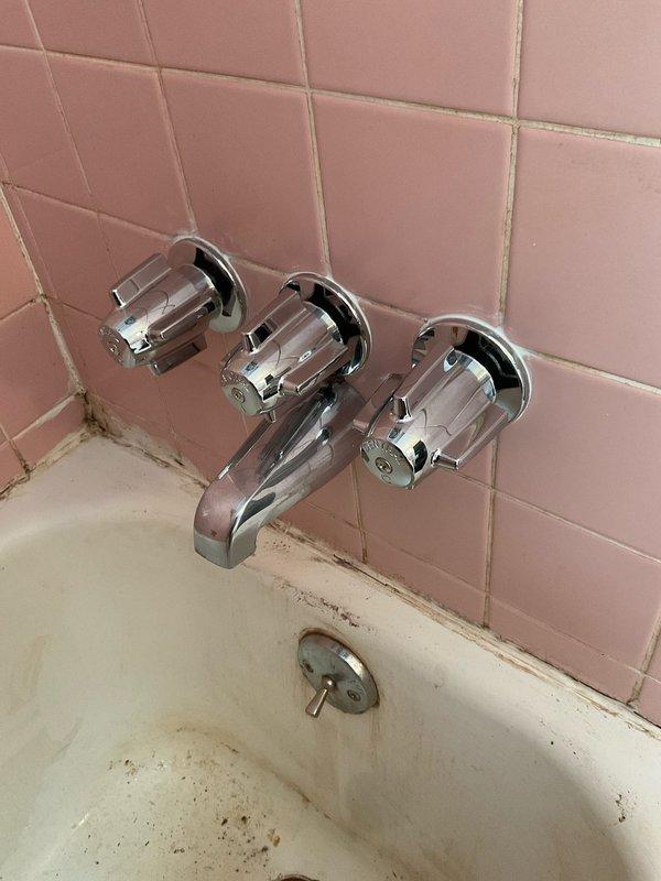 Installed customer-supplied shower fixtures in bathroom with existing pink tile surround and bathtub. Replaced three-handle wall-mounted faucet assembly and tub spout with new chrome fixtures, ensuring proper connections and testing for leaks upon completion.