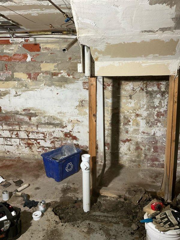 Responded to initial service call for multiple plumbing issues including shower head replacement and leaking pipes throughout the property. Upon arrival, conducted comprehensive inspection of plumbing system to identify all areas requiring immediate attention.

Addressed shower head replacement in bathroom, removing deteriorated fixture and installing new unit to restore proper water flow and eliminate leaking at connection point. Inspected associated supply lines and connections for additional leak sources.

Performed thorough assessment of basement plumbing infrastructure where multiple concerns were identified. Documented extensive corrosion on vertical drain pipes, with significant rust staining evident on pipe surfaces and heavy rust accumulation at floor penetration points. Observed substantial moisture damage and discoloration on concrete floor surrounding pipe bases, indicating active or recent water seepage from compromised pipe joints.

Identified corroded drain pipe in advan