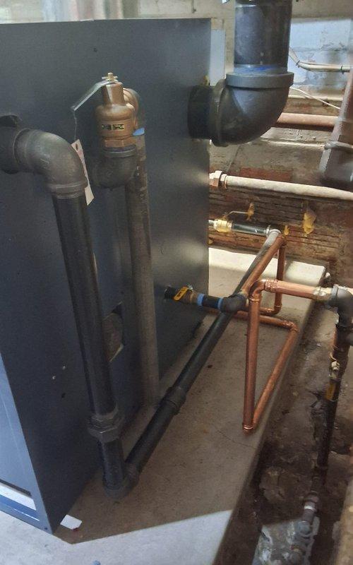 Completed full steam boiler replacement in commercial mechanical room, including removal of existing unit and installation of dual dark blue commercial-grade steam boilers positioned on concrete platform. Replaced boiler feed pump and feeder system with new equipment. Reconnected all supply and return steam lines using large-diameter black pipe with proper pitch and support, including horizontal distribution mains and vertical risers. Installed new copper piping network with appropriate valves, fittings, and pressure relief devices. Tested all connections for leaks, verified proper operation of feed system, and confirmed steam distribution to existing building infrastructure.