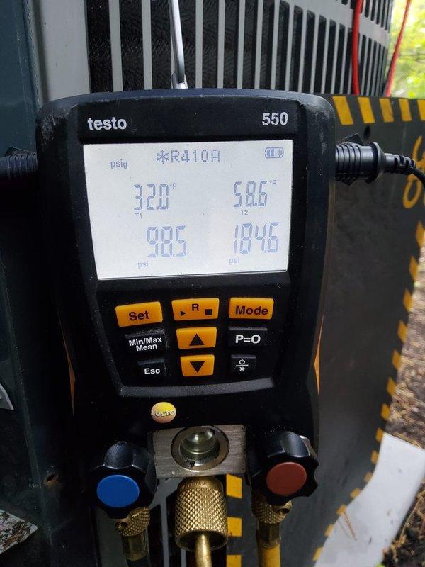 Performed preventive maintenance on two residential cooling systems, one located in the basement and one in the attic. Connected Testo 550 digital manifold gauges to measure system performance on R410A refrigerant systems. Recorded operating pressures of 98.5 psi on the low side and 184.6 psi on the high side, with corresponding temperatures of 32.0°F and 58.6°F. Verified proper refrigerant charge levels and system operation on both units. Inspected condenser coils and heat exchangers for cleanliness and airflow. Documented system parameters with photographs for maintenance records. Both systems operating within normal specifications upon completion of maintenance procedures.