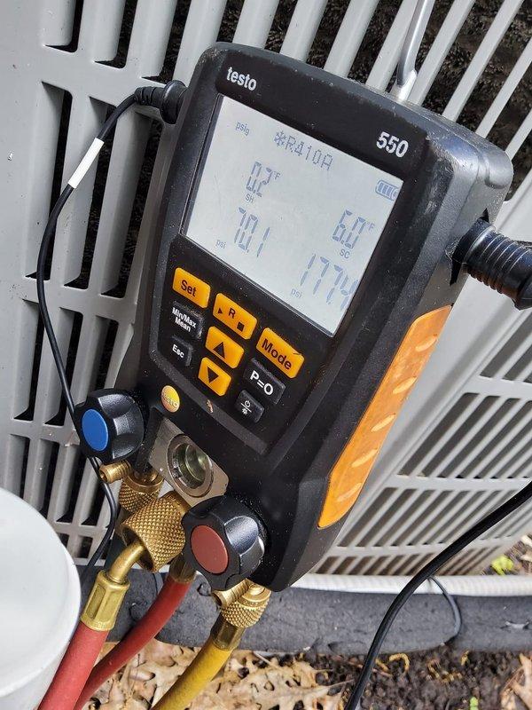 Performed preventive maintenance on two residential cooling systems, one located in the basement and one in the attic. Connected Testo 550 digital manifold gauges to measure system performance on R410A refrigerant systems. Recorded operating pressures of 98.5 psi on the low side and 184.6 psi on the high side, with corresponding temperatures of 32.0°F and 58.6°F. Verified proper refrigerant charge levels and system operation on both units. Inspected condenser coils and heat exchangers for cleanliness and airflow. Documented system parameters with photographs for maintenance records. Both systems operating within normal specifications upon completion of maintenance procedures.