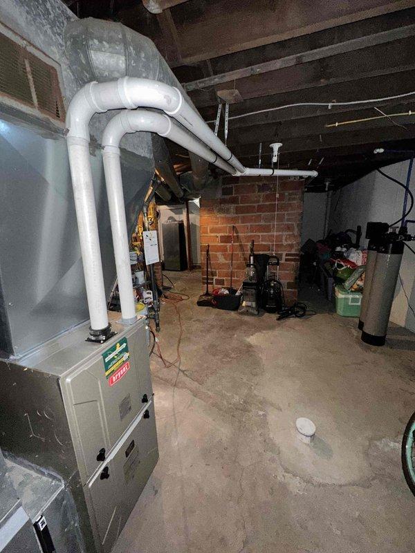 Completed plumbing repair service in basement utility area. Inspected and serviced plumbing fixtures including utility sink, copper water supply lines, and associated piping systems. Documented existing mechanical equipment configuration including furnace with PVC venting, water treatment units, and exposed plumbing infrastructure for service records.
