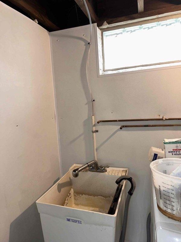 Completed plumbing repair service in basement utility area. Inspected and serviced plumbing fixtures including utility sink, copper water supply lines, and associated piping systems. Documented existing mechanical equipment configuration including furnace with PVC venting, water treatment units, and exposed plumbing infrastructure for service records.