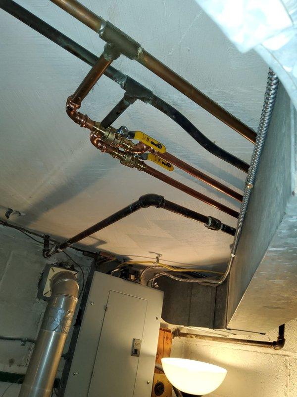 Completed water line reroute for hot water heater installation in basement utility area. Installed new copper supply piping with manifold configuration, brass shut-off valves, and proper pipe hangers to support horizontal runs across ceiling joists. Reconfigured existing plumbing infrastructure to accommodate relocated water heater position, ensuring proper clearances and code-compliant installation with accessible isolation valves for future service needs.