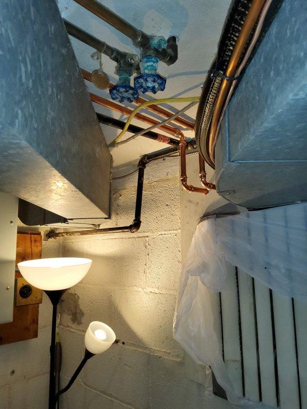 Completed water line reroute for hot water heater installation in basement utility area. Installed new copper supply piping with manifold configuration, brass shut-off valves, and proper pipe hangers to support horizontal runs across ceiling joists. Reconfigured existing plumbing infrastructure to accommodate relocated water heater position, ensuring proper clearances and code-compliant installation with accessible isolation valves for future service needs.