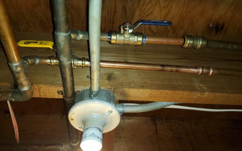 Responded to water leak call in HVAC system. Upon arrival, inspected basement plumbing infrastructure and located leak at copper pipe junction with compression fitting near blue-handled ball valve. Found moisture damage on wooden joists and identified compromised seal at brass fitting connection point. Tightened compression fittings, replaced worn ferrule, and tested all connections under pressure. Inspected adjacent PEX tubing, copper lines, and galvanized piping for additional leak sources. Verified water filtration system and pressure tank mounting were secure and not contributing to moisture issues. Cycled system multiple times to confirm repair integrity and no further leakage detected.
