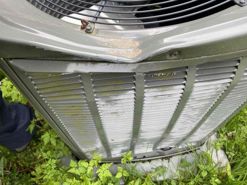 Responded to service call for outdoor condensing unit damaged by falling ice. Upon arrival, found condenser fan blade severely dented and fan motor operating improperly due to impact damage. Inspected top-mounted fan assembly and protective guard for structural integrity. Documented damage to fan blade and assessed unit for additional impact-related issues. Unit requires replacement of damaged condenser fan blade and motor verification to restore proper airflow and system operation.