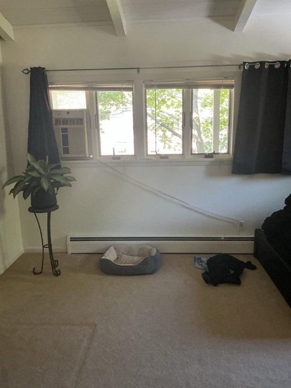 Conducted on-site assessment for mini split installation in residential space with vaulted ceiling and existing window air conditioning unit. Evaluated interior room layout, electrical access points, and attic space accessibility for potential indoor air handler and outdoor condenser placement. Documented current cooling system configuration and structural considerations including exposed beam construction and available mounting locations for optimal mini split system installation.
