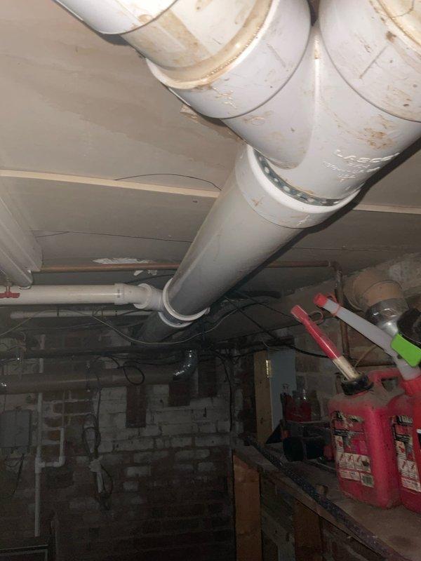 Responded to complaint of toilets gurgling into business below when flushed, with fixtures eventually losing ability to flush properly. Performed diagnostic inspection of plumbing system, focusing on drain and vent lines serving the affected toilets. Inspected exposed drainage piping in basement utility area, examining PVC drain lines, copper water supply lines, and venting configuration. Identified potential drainage obstruction or venting issue affecting proper waste evacuation from upper-level toilet fixtures. Documented existing plumbing infrastructure conditions with photographs showing pipe routing, support systems, and overall basement utility space configuration for further evaluation and repair recommendations.