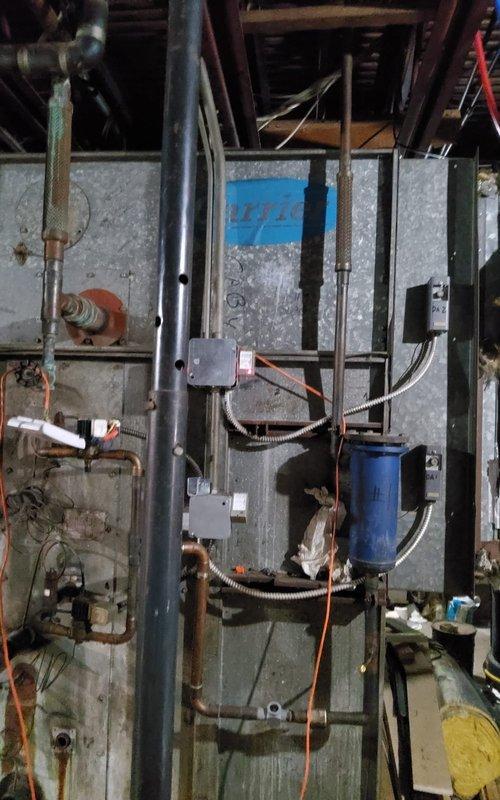 Responded to no-cooling call for 10+ year old air conditioning system located in basement serving first floor. Upon inspection, found aging A/C unit with visible wear and operational issues. Evaluated electrical components including capacitor, examined refrigerant lines and copper piping connections, and assessed overall system functionality. Documented equipment condition and mechanical room setup including ductwork, electrical panels, and ventilation components for diagnostic and repair recommendations.