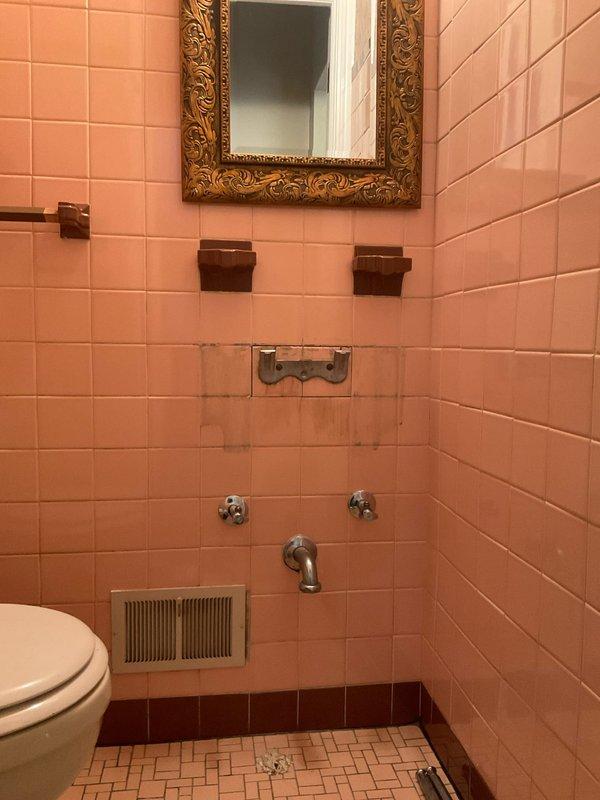 Replaced shelf-mounted faucet assembly in vintage bathroom with peachy-pink tile work. Removed existing worn fixture, installed new faucet hardware, and conducted thorough testing to verify proper water flow and drainage functionality.