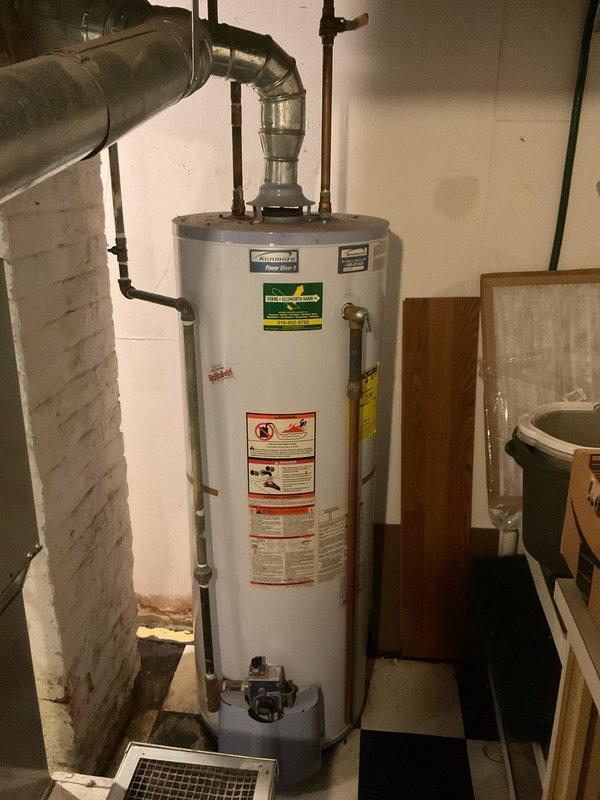 Responded to emergency service call for actively leaking tanked water heater in 9-year-old residence. Upon arrival, inspected gas-fired water heater unit and identified source of active leak from tank body, indicating internal tank failure. Confirmed customer had shut off water supply and gas valve as safety precaution. Documented existing conditions with photographs showing water heater installation, gas control valve assembly, copper supply line connections, and evidence of water damage on concrete floor. Evaluated temperature and pressure relief valve, gas connections, and overall system configuration. Advised customer that tank replacement would be necessary due to internal corrosion and tank integrity compromise. Also assessed reported minor leak at kitchen sink fixture for future repair consideration.