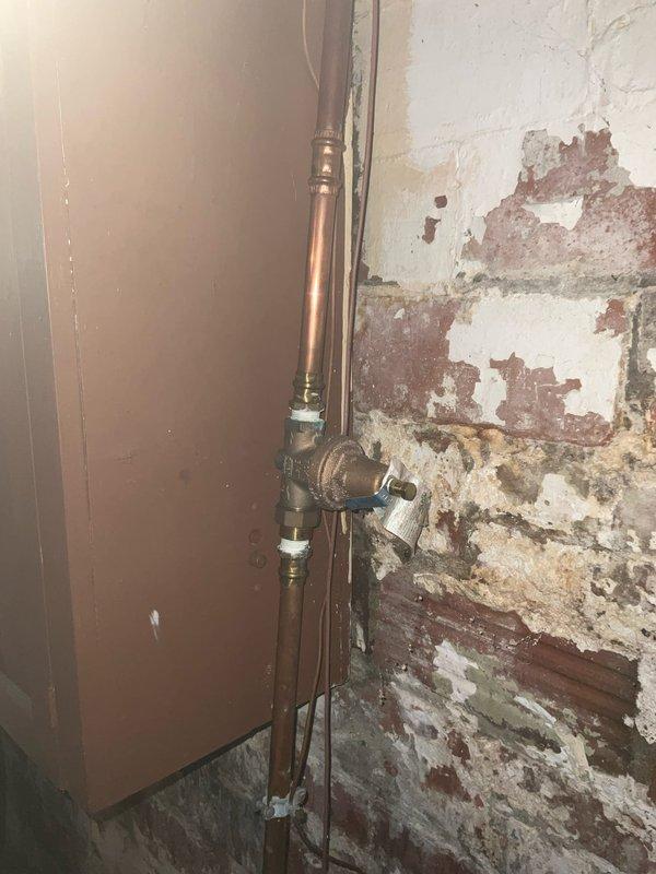 Responded to service call for kitchen and bathroom faucet repairs in 90-year-old residential property. Upon arrival, inspected kitchen double-basin stainless steel sink with single-handle faucet and separate pull-out side sprayer. Evaluated faucet operation, tested water flow, and checked for leaks at connections and base mounting. Proceeded to bathroom where exposed copper supply lines and shut-off valves were visible due to deteriorated wall conditions. Assessed plumbing infrastructure including vertical copper piping with brass fittings and valves. Performed necessary repairs to restore proper faucet function in both locations, addressing issues common in aging plumbing systems. Documented conditions with photographs for service records.