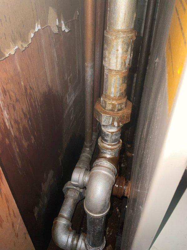 Responded to emergency water leak in century-old residential property. Upon arrival, conducted thorough inspection of basement plumbing system and identified active leak source at corroded copper supply line with severely deteriorated threaded galvanized steel fittings. The affected piping displayed extensive oxidation, greenish-yellow corrosion patterns, and compromised joint integrity consistent with age-related material failure.

Shut off main water supply to prevent further water damage. Removed damaged section of corroded copper pipe and failing galvanized steel coupling assembly. Replaced compromised piping with new copper supply line using proper soldering techniques and installed new brass fittings to ensure watertight connections. All joints were cleaned, fluxed, and soldered to code specifications.

Pressure tested the repaired section to verify system integrity and confirm no additional leaks were present. Restored water service and monitored all connections for proper opera