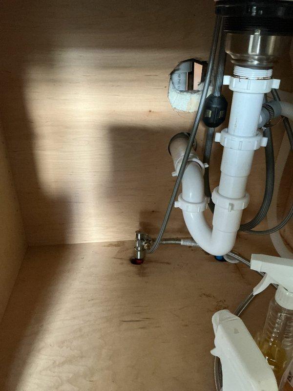 # Plumbing Service - Water Leak

## Summary
Return visit to address recurring kitchen sink leak previously serviced two months prior; inspected and addressed drainage system issue beneath sink.

## Work Performed

Responded to callback for recurring kitchen sink leak in 106-year-old residence. Upon arrival, accessed under-sink cabinet to inspect plumbing assembly consisting of white PVC drainage pipes, P-trap configuration, garbage disposal unit, and dishwasher drain connection via black corrugated flexible hose.

Conducted thorough examination of all drain pipe connections, fittings, and couplings throughout the assembly. Inspected vertical tailpiece connection to garbage disposal unit, P-trap joints, and multiple white plastic fittings for signs of deterioration, improper sealing, or loosening since previous service visit. Checked mounting clips and support brackets securing pipes to cabinet structure for proper positioning and stability.

Evaluated chrome shut-off valve and supply l