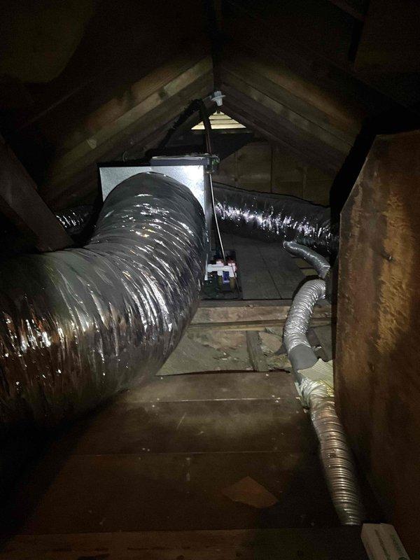 Conducted on-site assessment for mini split system replacement in residential attic space. Documented existing HVAC air handler unit and associated ductwork configuration, including flexible black ducting and metal components. Evaluated attic installation conditions, structural support, and current system placement for replacement planning. Photographed equipment positioning, ductwork routing, and available workspace to develop comprehensive replacement estimate.