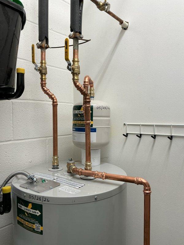 Replaced existing 40-gallon electric water heater with new 50-gallon electric unit equipped with fast recovery heating elements. Installation included connecting copper supply lines with brass fittings, installing flexible metallic connector hose, mounting expansion tank to wall, and configuring all necessary plumbing connections to existing black pipe system. All components were properly secured and tested for operational performance.
