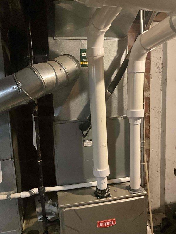 Conducted comprehensive assessment of existing residential HVAC system for complete replacement estimate. Evaluated aging Bryant furnace/air handler unit located in basement mechanical room, noting current ductwork configuration with flexible metal ducting and associated PVC venting components. Inspected outdoor condensing unit, which showed significant weathering, dirt accumulation, and vegetation encroachment around the base and sides. Documented current system layout including electrical conduit routing, concrete pad condition, and equipment accessibility concerns. Photographed both indoor and outdoor components to provide detailed visual documentation of existing installation for replacement proposal. Recommended prompt scheduling to accommodate customer timeline requirements.