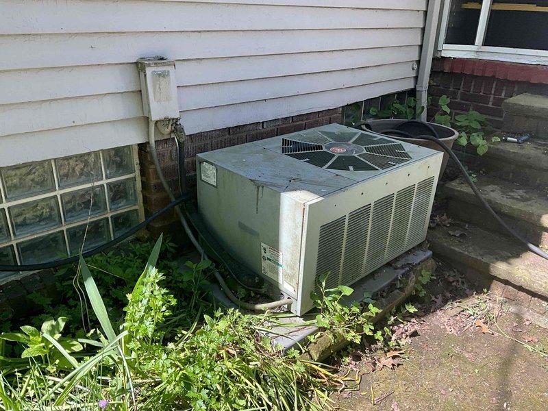 Conducted comprehensive assessment of existing residential HVAC system for complete replacement estimate. Evaluated aging Bryant furnace/air handler unit located in basement mechanical room, noting current ductwork configuration with flexible metal ducting and associated PVC venting components. Inspected outdoor condensing unit, which showed significant weathering, dirt accumulation, and vegetation encroachment around the base and sides. Documented current system layout including electrical conduit routing, concrete pad condition, and equipment accessibility concerns. Photographed both indoor and outdoor components to provide detailed visual documentation of existing installation for replacement proposal. Recommended prompt scheduling to accommodate customer timeline requirements.