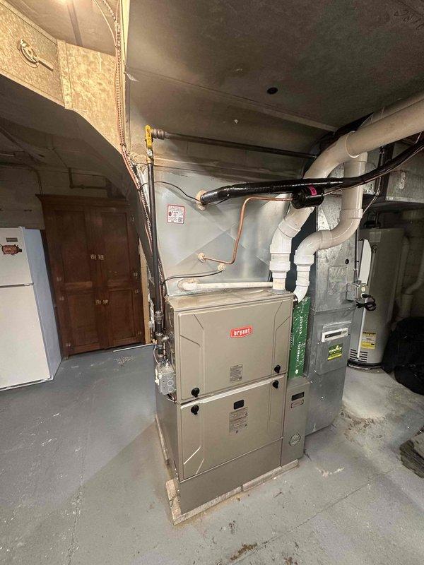 # HVAC Complete System Installation

Successfully completed a full HVAC system installation in a residential basement mechanical room. Installed a new Bryant furnace as the primary heating unit, complete with all necessary ductwork connections including white rectangular supply ducts and black flexible ductwork. Integrated copper refrigerant lines and white PVC condensate drainage piping to ensure proper system operation and code compliance.

The installation included proper placement and mounting of the furnace unit on the concrete basement floor, with all required electrical connections, gas line hookups, and ventilation components. Connected the system to existing ductwork infrastructure at the ceiling level, ensuring proper airflow distribution throughout the residence. Installed filtration components and verified all access panels were properly secured with appropriate warning labels visible for future service needs.

All equipment was tested for proper operation, including verifi