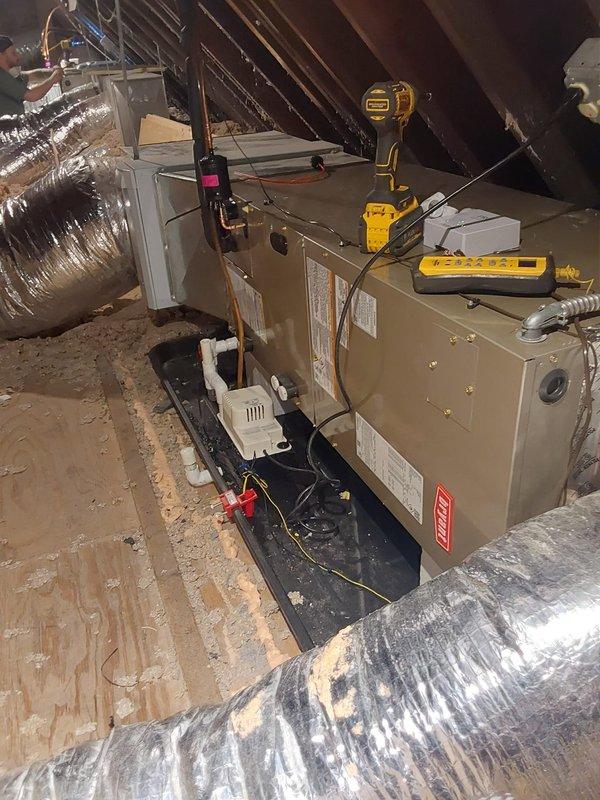 Completed full installation of dual-zone air conditioning system at residential property. Removed existing equipment and installed two complete AC systems in attic space, including outdoor condensing units, indoor air handlers, safety drain pans with wet switches, and programmable thermostats.

Positioned both outdoor condensers on level gravel pad adjacent to exterior stone wall, ensuring proper clearance for airflow and future maintenance access. Mounted units on vibration-dampening pads and completed all refrigerant line connections and electrical hookups per manufacturer specifications. Verified adequate spacing between units for optimal performance.

In attic, installed two air handler units on secondary drain pans with integrated wet switch float sensors to prevent water damage from potential condensate overflow. Configured PVC condensate drainage lines with proper pitch and secured all connections. Connected supply and return ductwork using insulated flexible ducting, ensuring p