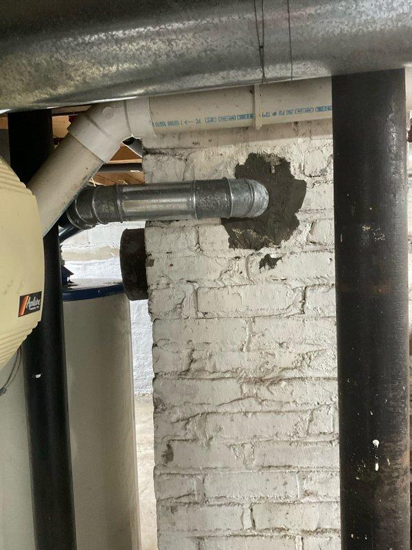Responded to service call for water heater flue pipe repair in century-old residential property. Upon inspection, identified deteriorated flue pipe connection at tanked water heater with compromised sealing around penetration point through masonry wall. Repaired flue pipe assembly to ensure proper venting of combustion gases and restored code-compliant connection between water heater exhaust and vertical vent stack. Verified secure mounting, proper draft operation, and eliminated potential carbon monoxide hazard. All work completed to current plumbing and safety standards.