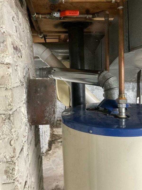 Responded to service call for water heater flue pipe repair in century-old residential property. Upon inspection, identified deteriorated flue pipe connection at tanked water heater with compromised sealing around penetration point through masonry wall. Repaired flue pipe assembly to ensure proper venting of combustion gases and restored code-compliant connection between water heater exhaust and vertical vent stack. Verified secure mounting, proper draft operation, and eliminated potential carbon monoxide hazard. All work completed to current plumbing and safety standards.