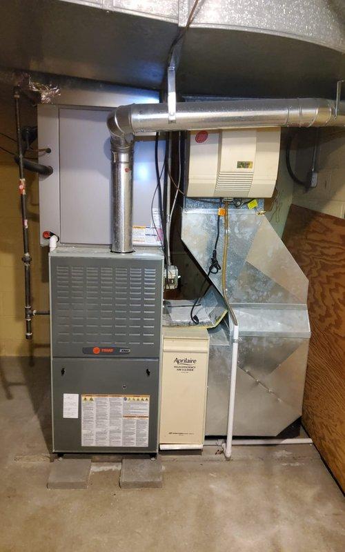 Responded to no-cool service call for 11-year-old Trane central air conditioning system with PA13A060 E outdoor unit. Upon arrival, confirmed outdoor condenser fan was not operating, resulting in no cooling to entire residence. Inspected indoor furnace and air handler components, verified proper thermostat operation and settings. Proceeded to outdoor unit for diagnostic evaluation. Found condenser unit partially obscured by overgrown vegetation including climbing vines and shrubs, which may restrict airflow and contribute to premature component failure. Diagnosed failed capacitor preventing condenser fan motor from starting. Replaced dual run capacitor with manufacturer-approved replacement part, restoring proper operation to condenser fan motor. Tested system operation through complete cooling cycle, verified proper amperage draw on compressor and fan motor, confirmed adequate airflow and temperature differential across evaporator coil. Recommended vegetation management around outdoor