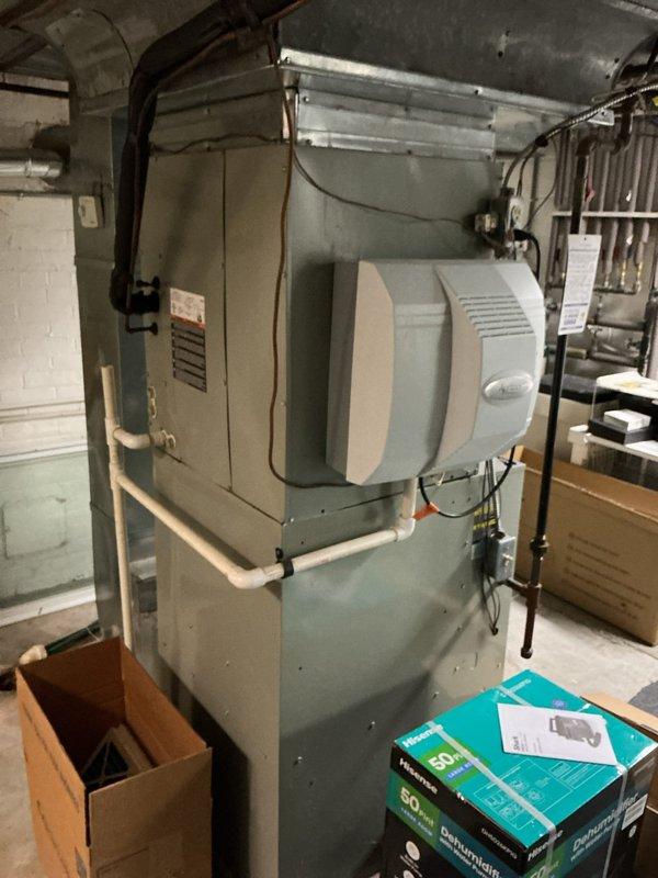Completed comprehensive HVAC system replacement estimate for residential property equipped with dual air conditioning units, furnace, and heat pump system. Documented existing basement mechanical room installation including gray metal furnace/air handler unit with integrated humidifier, PVC drainage piping, copper refrigerant lines, and associated ductwork infrastructure to provide accurate replacement specifications and equipment sizing recommendations.
