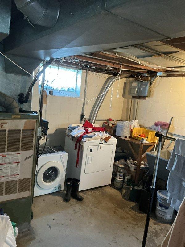 Completed on-site assessment for furnace replacement in residential basement utility room. Documented existing older model furnace unit with connected ductwork system, including sheet metal supply ducts, blue metal plenum, and wall-mounted humidifier or air treatment device. Photographed current HVAC configuration and mechanical room layout to prepare comprehensive replacement estimate for homeowner.