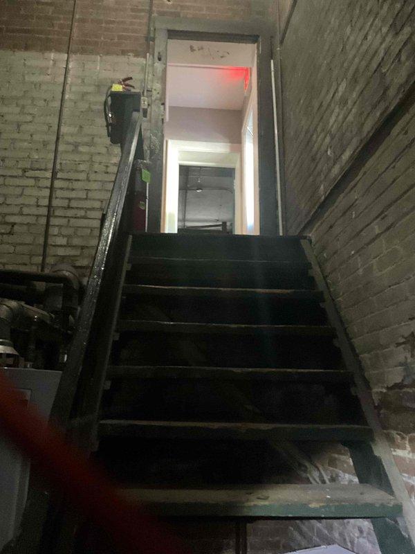 Conducted comprehensive site assessment for commercial steam boiler replacement in industrial mechanical room with exposed brick walls and concrete flooring showing moisture damage. Evaluated existing equipment condition, documented deteriorated cylindrical boiler component with visible rust and corrosion, assessed piping infrastructure and structural supports, and photographed installation environment including access stairwell. Provided detailed estimate for complete boiler system replacement.