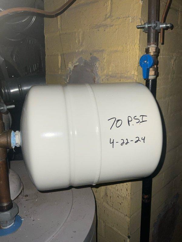 Provided free estimate for replacement of 24-year-old 50-gallon natural gas water heater experiencing active leakage at base. Upon inspection, confirmed significant water pooling on concrete floor beneath unit with visible moisture damage and discoloration on tank exterior. Age and condition of existing water heater indicate end of serviceable life. Documented current installation configuration including copper supply piping connections and existing pressure tank system marked at 70 PSI. Reviewed replacement options and specifications for new 50-gallon tank installation to restore reliable hot water service.