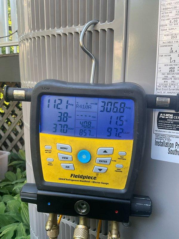 Completed spring maintenance on a one-year-old Carrier R-410A cooling system. Performed comprehensive system diagnostics using refrigerant manifold gauges, recording operating pressures of 112.1 PSIG suction and 306.8 PSIG discharge with temperature differentials within normal parameters. Inspected condenser coil condition, verified proper refrigerant charge levels, and confirmed all manufacturer specifications and safety labels were intact and legible on the outdoor unit.