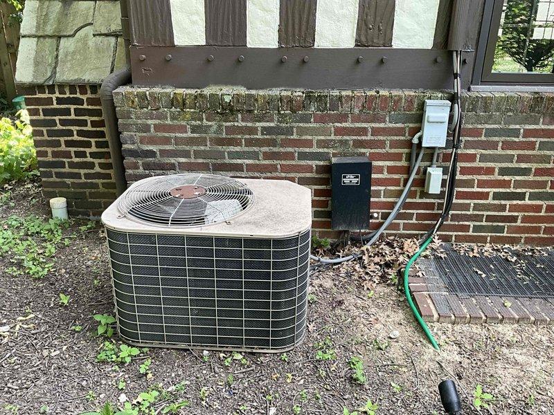Conducted on-site evaluation for air conditioning system replacement at residential property. Assessed existing outdoor condenser unit positioned against exterior brick wall, noting equipment age and condition. Documented current system configuration including electrical disconnect box, conduit routing, and power supply connections. Inspected interior electrical panel in unfinished area to verify available electrical capacity and circuit breaker specifications for new equipment installation. Photographed existing equipment placement, clearances, and surrounding conditions to develop accurate replacement proposal. Evaluated installation requirements including electrical service compatibility, mounting surface conditions, and accessibility for future maintenance.