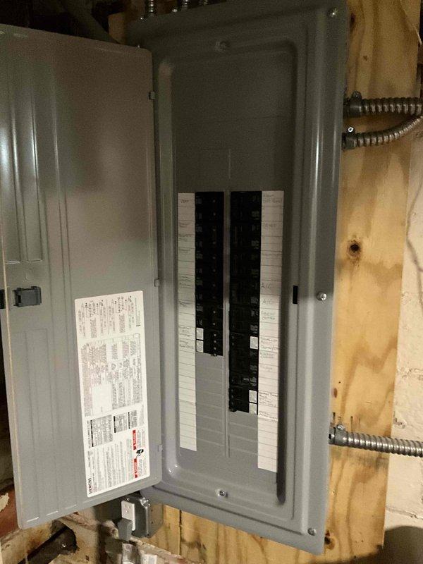 Conducted on-site evaluation for air conditioning system replacement at residential property. Assessed existing outdoor condenser unit positioned against exterior brick wall, noting equipment age and condition. Documented current system configuration including electrical disconnect box, conduit routing, and power supply connections. Inspected interior electrical panel in unfinished area to verify available electrical capacity and circuit breaker specifications for new equipment installation. Photographed existing equipment placement, clearances, and surrounding conditions to develop accurate replacement proposal. Evaluated installation requirements including electrical service compatibility, mounting surface conditions, and accessibility for future maintenance.