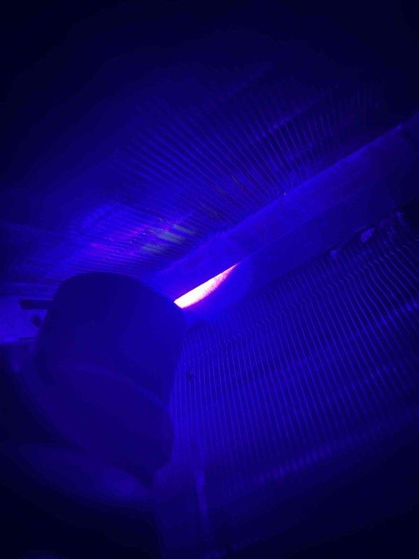 Performed return visit to inspect for UV dye previously injected into system to locate refrigerant leak on two-year-old unit experiencing ongoing cooling issues. Utilized UV light to scan evaporator coil and refrigerant lines for dye traces, documented findings with diagnostic photos showing blower assembly and unit specifications (Model CAPMPZ17ALA6AAA, R-410A refrigerant system). No visible dye leakage detected at time of inspection, indicating leak may be intermittent or located in areas requiring further disassembly for complete evaluation.