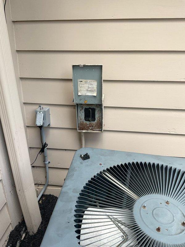 Responded to no-cooling complaint on 16-year-old Goodman central air conditioning system. Upon arrival, confirmed indoor blower operating normally but outdoor condenser fan failed to spin. Compressor attempted to start and hummed but unit overheated and shut down on safety within minutes. Performed diagnostic evaluation of outdoor unit including visual inspection and electrical testing. Confirmed condenser fan motor seized and would not spin even when manually rotated. Tested dual-run capacitor and found failed capacitor unable to provide starting voltage to fan motor. Inspected contactor, wiring connections, and disconnect switch, noting significant corrosion on exterior disconnect box but functional electrical connections. Diagnosed failed condenser fan motor and defective capacitor as root cause of system failure preventing outdoor unit operation and cooling capacity. Documented equipment condition with photos showing outdoor unit configuration, electrical components, and weathered 